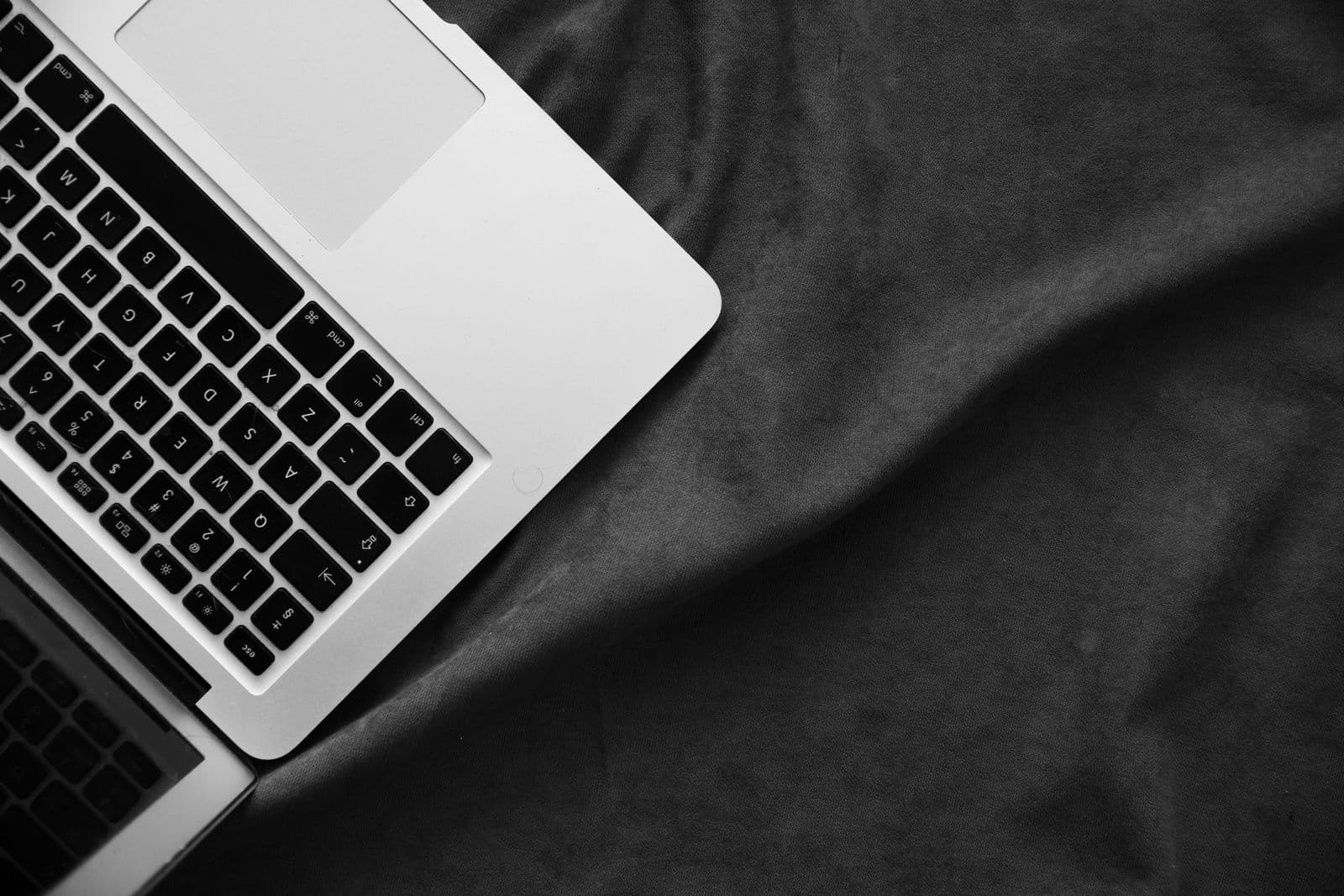 An open laptop resting on dark fabric with space to write