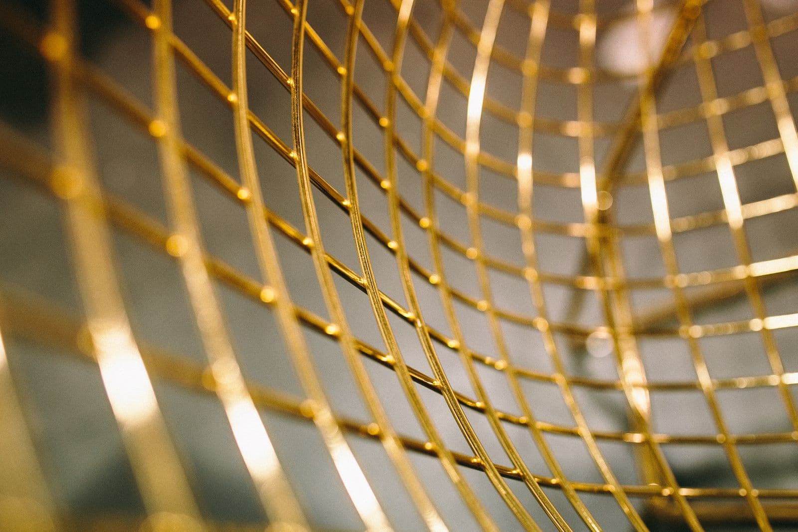 Abstract curved gold metal mesh forming a fine geometric pattern